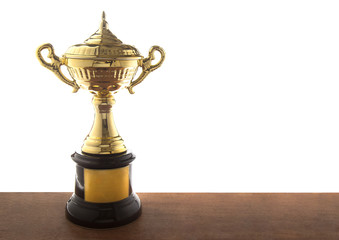 Fototapeta na wymiar Golden trophy on wooden table isolated over white background. Winning awards with copy space.