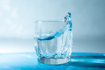 glass of splashing water on a blue background