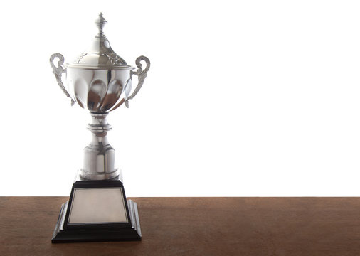 Silver trophy on wooden table isolated over white background. Winning awards with copy space.