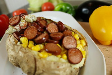 Kumpir - Turkish baked potato with butter, cheese, corn, beef sausage, vegetable salad and spices. This kumpir is traditional turkish food isolated on white background