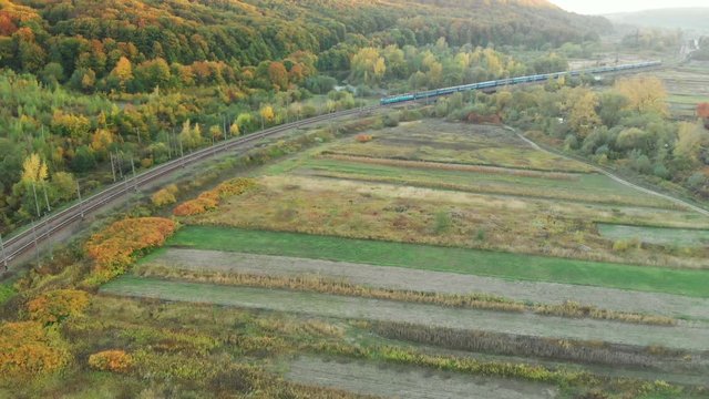 Aerial view of railway and train going through autumn mountains