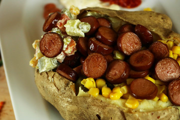 Kumpir - Turkish baked potato with butter, cheese, corn, beef sausage, vegetable salad and spices. This kumpir is traditional turkish food isolated on white background
