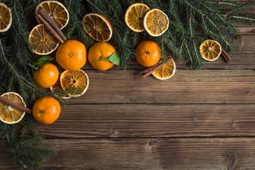 Obraz na płótnie Canvas Christmas composition. tangerines and fir branches on wooden background. free space for inscription