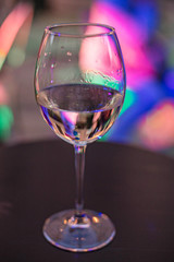 Two glass of wine on the table on the colorful lights background. Glass of white wine and glass of pink wine close up.