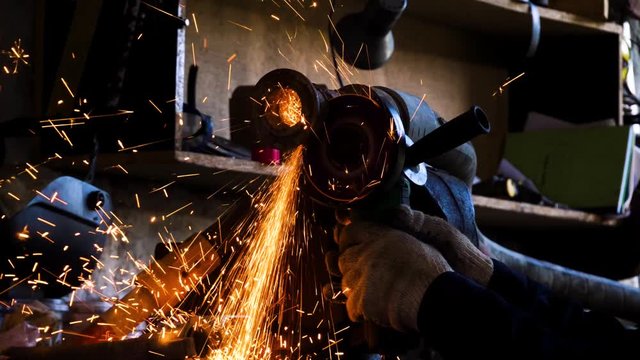 Close-up of worker cutting metal with grinder. Frame. Sparks while grinding iron. Circular cutting disc cuts of metal