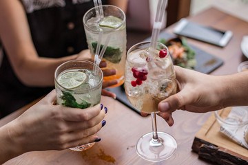 Group of friends having fun and drink cocktails. Cheers glasses in the hands. Summer mood in Minsk,...