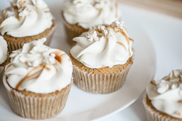 Beautiful white cupcakes with salty caramel on a white plate.