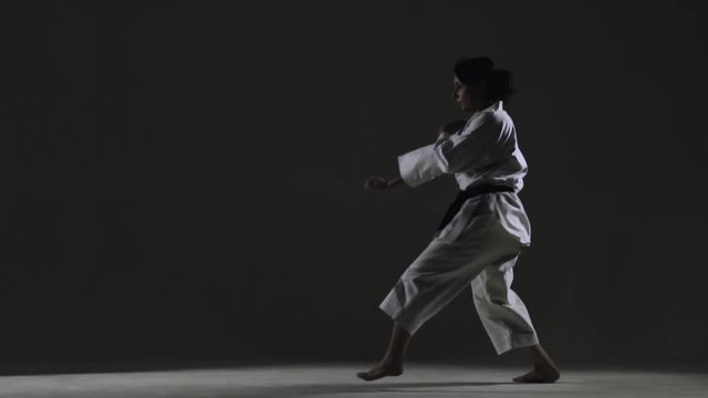 girl practicing karate, wearing kimono, on gray background. slow motion recorded at 120fps
