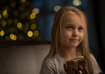 child with Christmas gifts on garland background
