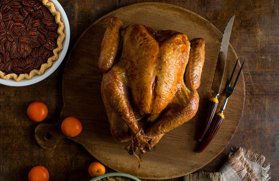 Overhead view of baked turkey on wooden cutting board