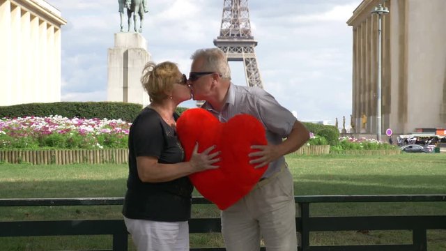 Senior couple kissing in front of Eiffel tower on valentines day in 4k slow motion 60fps