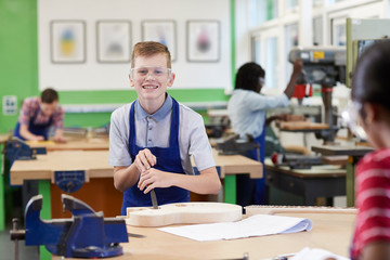 Portrait Of Male High School Student Building Guitar In Woodwork Lesson