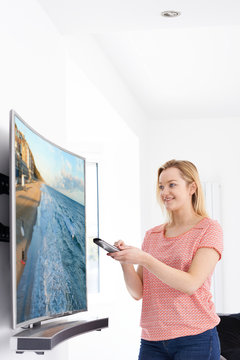 Young Woman With New Curved Screen Television At Home