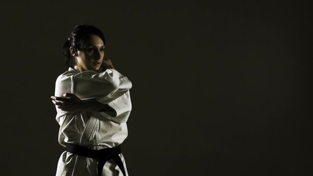 girl practicing karate, wearing kimono, on dark background. slow motion recorded at 120fps