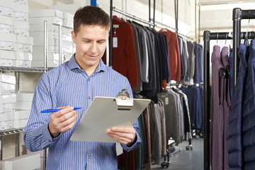 Owner Of Start Up Fashion Business In Warehouse With Clipboard