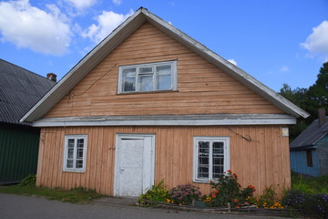 Traditionelles, hellbraunes Holzhaus mit weißen Fenstern vor strahlend blauem Himmel