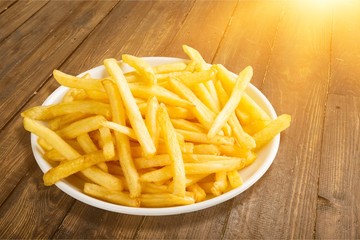 Plate of french fries on wooden table