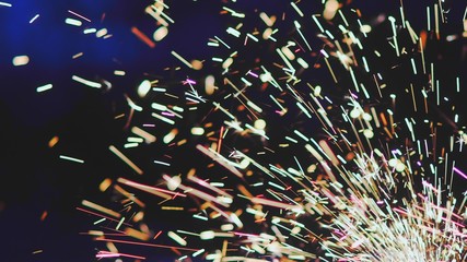 Close Up Shot Of Melting Metal Particles Emitting Colorful Sparks From A Metal Grinding Machine.