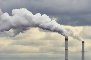 Smoking Industrial Chimneys Of A Power Plant Polluting The Air At Dawn With Grey Clouds.