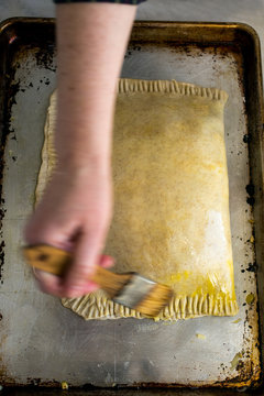 Close up of man's hand greasing cabbage torta with basting brush