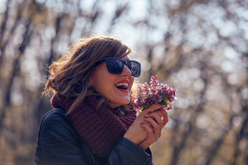 Cute young girl smelling nice bouquet of flowers in nature.