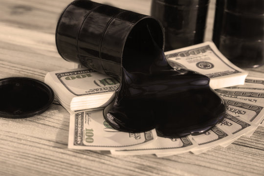 barrels of oil, us dollars on the background of a wooden table. the fuel industry, the oil products market.