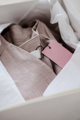 White opened box with wrapping paper and pink linen cloth and label. Copyspace for text