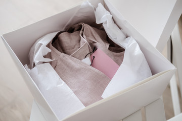 White opened box with wrapping paper and pink linen cloth and label. Copyspace for text