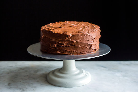 Close up of devil's food cake with black pepper buttercream on cake stand