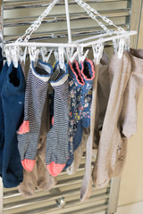 Different clean socks hang and dry on a heater. Concept: housework.