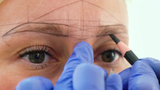 Beautician drawing new eyebrow shape for microblading on female face closeup. Cosmetologist preparing for permanent tattooing