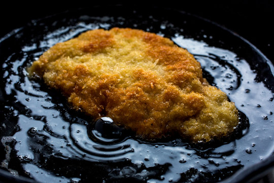 Close up of pork schnitzel frying in oil