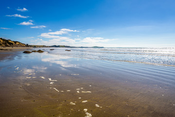 Beautiful deserted empty beach landscape with reflection of the sky on the water. Moeraki Boulders on the Koekohe beach, Eastern coast of Otago, South Island. New Zealand