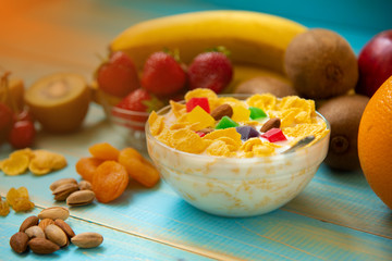 Tasty cornflakes with milk and fruits in glass bowl