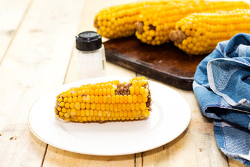 Fresh cooked corn on cutting board  on rustic wooden table