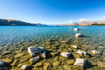 Crystal clear fresh glacier water at the pristine Lake Tekapo. Peaceful and calm mountain landscape, Mackenzie Basin, Canterbury, New Zealand.