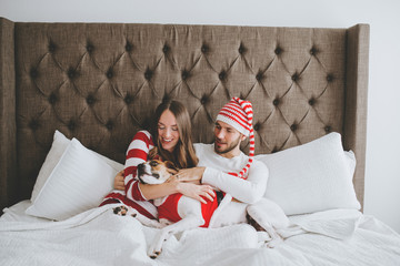 Happy Christmas couple snuggled in bed with puppy