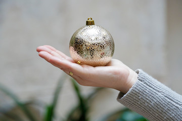 Close up of woman hand showing a gold christmas ball