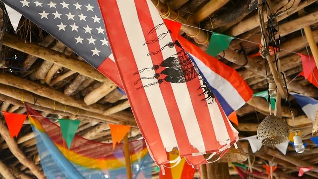 Decorative national flags of different countries hanging on strings in wooden tropical bungalow. Exotic rasta bar interior. Summer beach house on Koh Phangan island, Thailand.