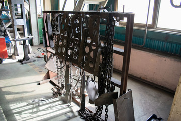 Chains and auxiliary metal tools in the forge’s industrial workshop. Machine shop of metallurgical works indoors room.