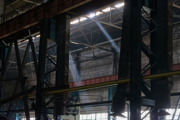 Rays of light in a dark industrial workshop of an industrial plant. Warehouse of heavy iron and...
