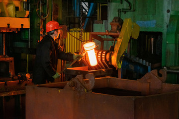 Hot iron in smeltery held by a worker. High precision hot forging product, automotive part...