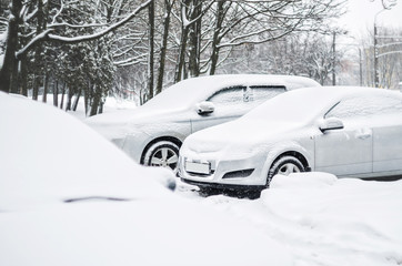 Cars in the parking lot are covered with a thick layer of snow. Concept: winter weather and car owner confrontation