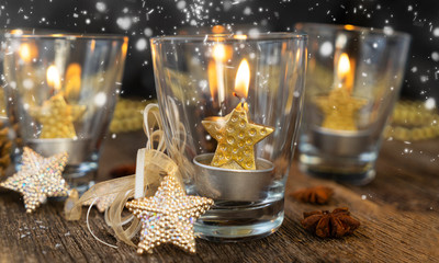 Glowing Christmas advent golden star burning candles in glass with snow