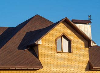 Modern multilevel rooftop of the brick mansion with window, chimney and rain gutters