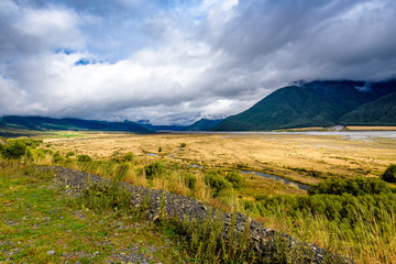 Fototapeta na wymiar Beautiful mountain and countryside green and yellow landscape. Hills, plains, meadows, prairie, fields and river flowing. Waimakariri river valley, near Arthur's Pass and Lake Pearson, New Zealand.