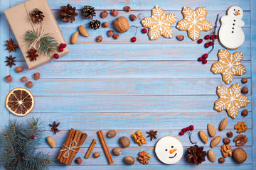 Christmas gingerbread cookies, gift box, nuts and spices on wooden background with copy space for text. Holiday, celebration, festive and cooking concept. New Year and Christmas composition, postcard