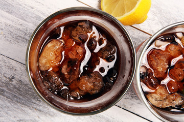 Softdrink with ice cubes, lemon and straw in glass