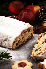 Traditional European Christmas pastry, fragrant home baked stollen, with spices and dried fruit. Sliced on rustic table with xmas tree branches and decorations