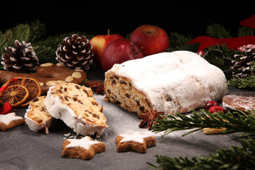 Traditional European Christmas pastry, fragrant home baked stollen, with spices and dried fruit. Sliced on rustic table with xmas tree branches and decorations